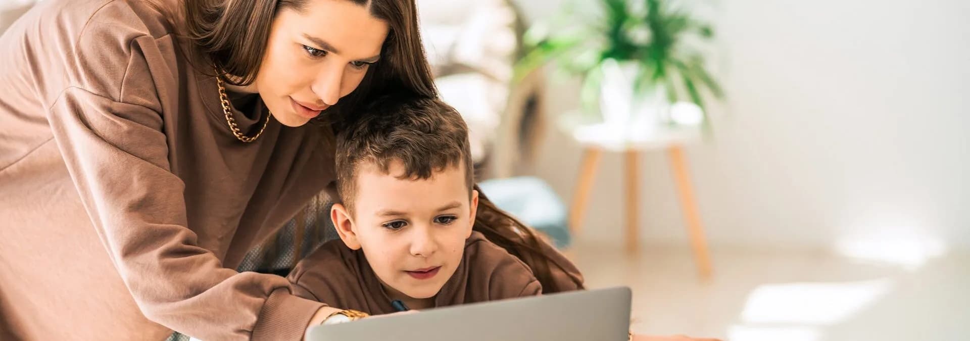 A parent helping a young student work on a laptop at home